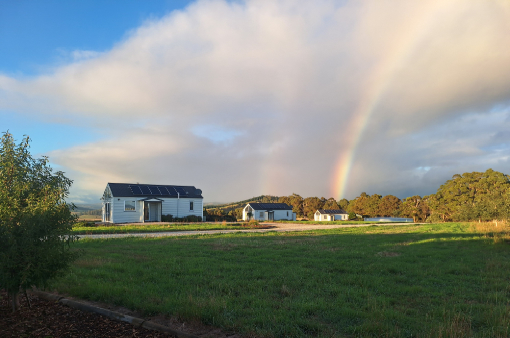 Three cottages, early morning, rainbow behind the last cabin
